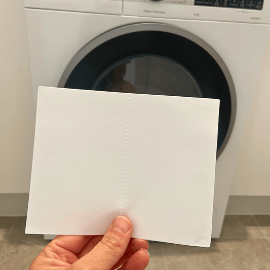 Fragrance-free laundry sheet held in front of a washing machine for sensitive and eczema-prone skin